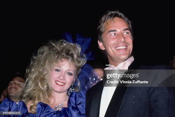 American actress Patti D'Arbanville, wearing a blue off-shoulder evening gown with a sheer blue hairbow, and American actor Don Johnson, who wears a...