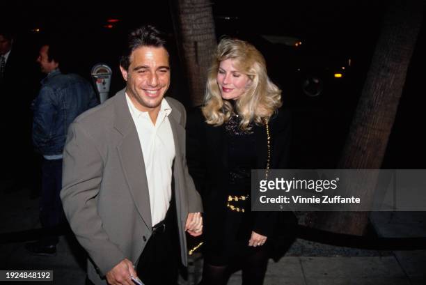 American actor Tony Danza, wearing a dark grey blazer over a white shirt which is open at the collar, holding hands with his wife, Tracy, who wears a...