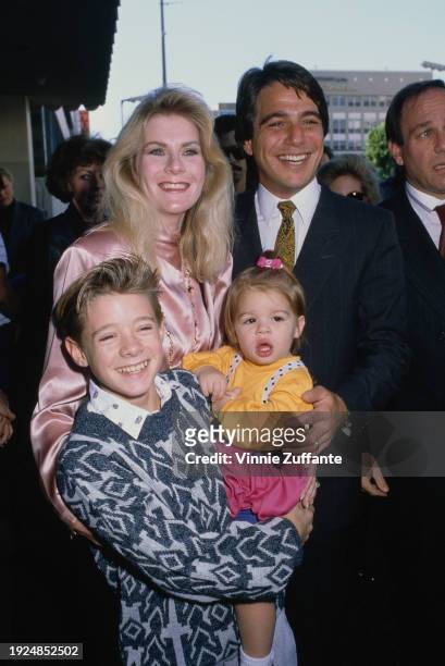 American actor Tony Danza with his wife, Tracy, and American child actor Danny Pintauro, who holds the Danza's daughter, Katherine, attend Tony...