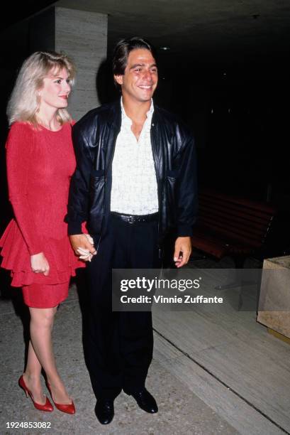 American actor Tony Danza, wearing a black leather jacket, holding hands with his wife, Tracy, who wears a red dress, United States, circa 1995.