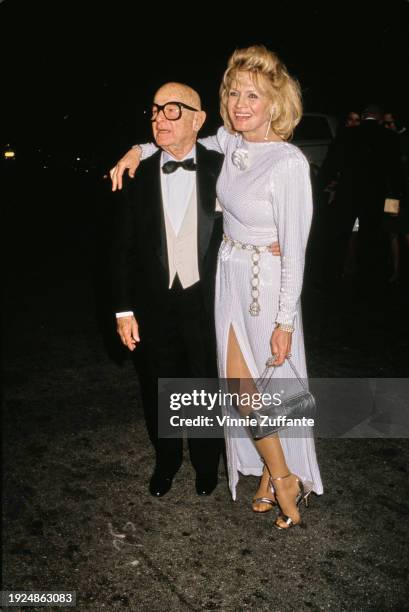 American lawyer and talent agent Irving Paul Lazar, wearing a tuxedo and bow tie, and American actress Angie Dickinson, who wears a white bateau-neck...