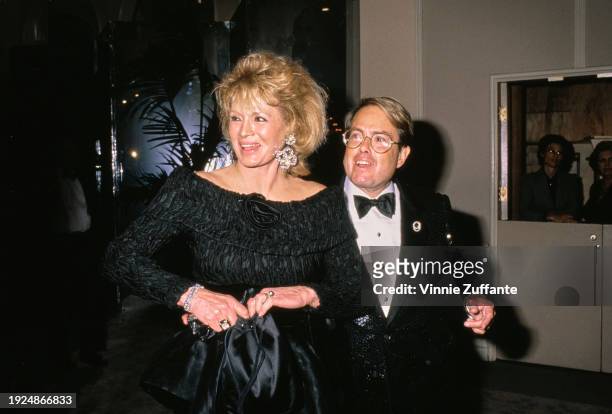 American actress Angie Dickinson, wearing a black off-shoulder outfit, and American film producer Allan Carr, who wears a tuxedo and bow tie, attend...