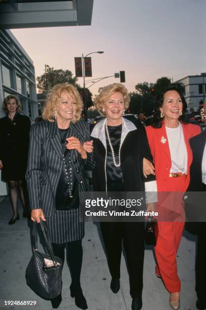 American actress Angie Dickinson, wearing a dark grey pinstripe suit with a black crew-neck top, and American socialite Barbara Sinatra, who wears a...