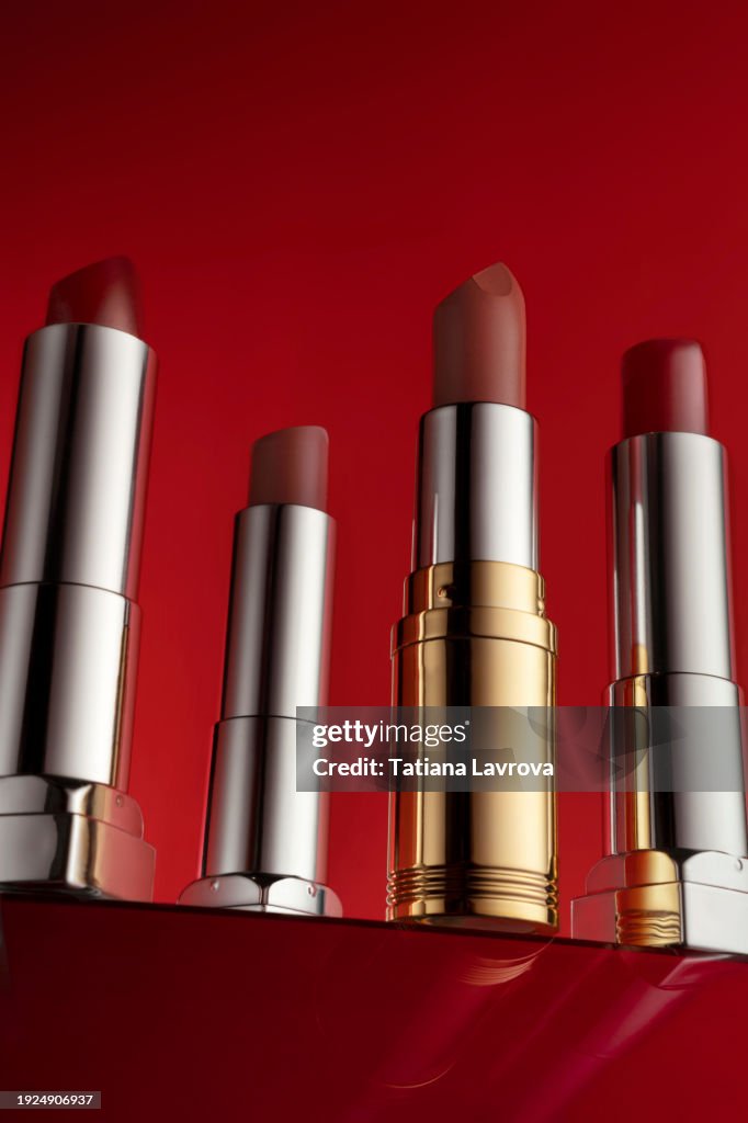 Set of lipsticks on rich red background. Luxury commercial photography with copy space. Close up, hero shot view. Mockup template with space for your logo, text, design elements