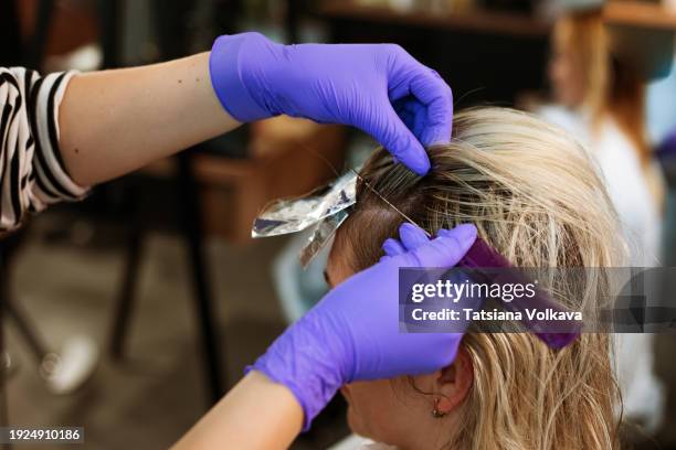hands of unidentifiable professional hairstylist gently brush through locks of female - frau haarsträhne blond beauty stock-fotos und bilder