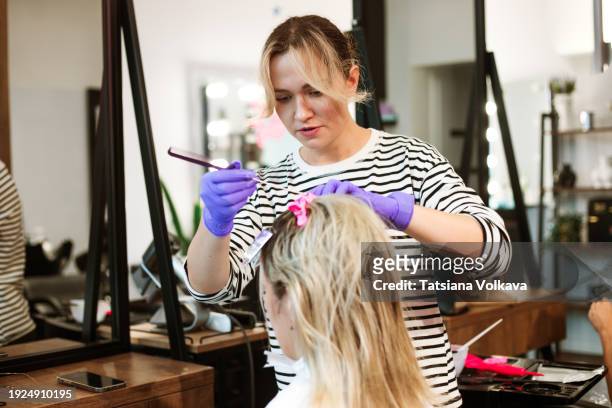 hands of an unidentified professional hairdresser gently combing a woman's locks - frau haarsträhne blond beauty stock-fotos und bilder