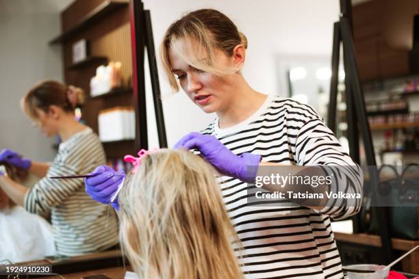 unrecognizable woman undergoing a hair coloring transformation in the comfortable confines of a hair salon, seated comfortably in the styling chair. - frau haarsträhne blond beauty stock-fotos und bilder