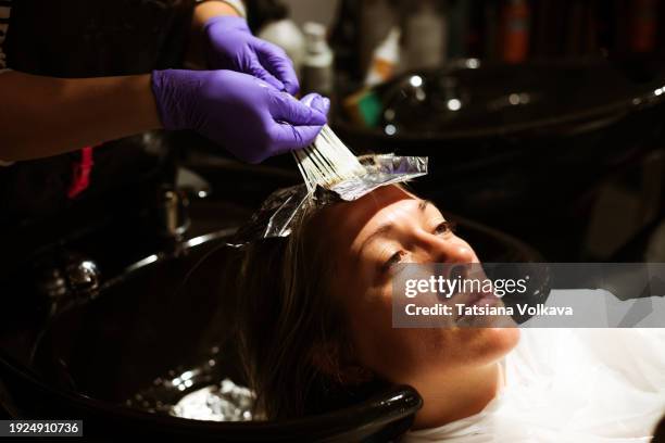 relaxing hair care ritual: enjoying a tranquil moment, a client experiences a soothing hair wash administered by a skilled hairdresser in the serene environment of a beauty salon. - administered stock pictures, royalty-free photos & images