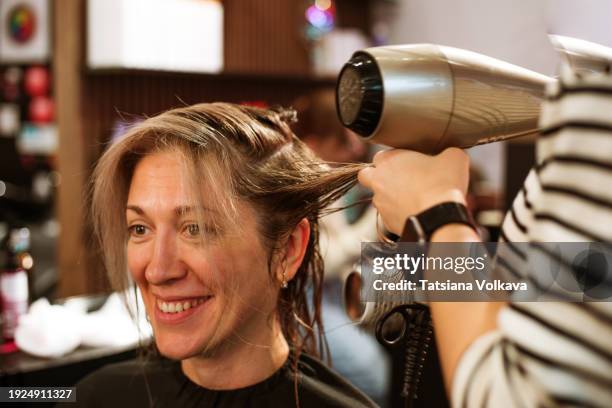 artistry in action: a hairstylist showcases their skill, working with a client's hair using a hairdryer, crafting a personalized and beautiful look in the salon. - haardroger stockfoto's en -beelden