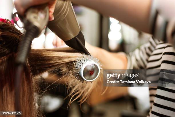 a hairstylist, with finesse, wields a hairdryer in a styling session, adding elegance to a transformative beauty journey. - secar o cabelo com secador imagens e fotografias de stock