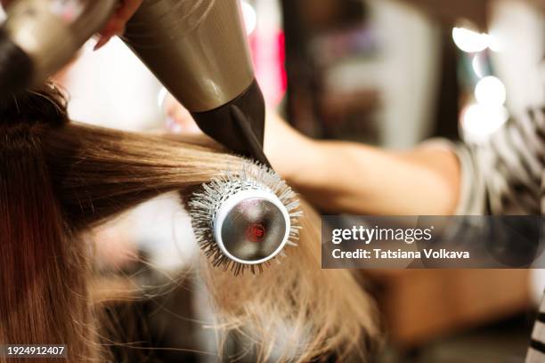 beauty unfolds in a hairstylist's hands, using a hairdryer for the final touch in a session of elegance and haircare. - frau haarsträhne blond beauty stock-fotos und bilder