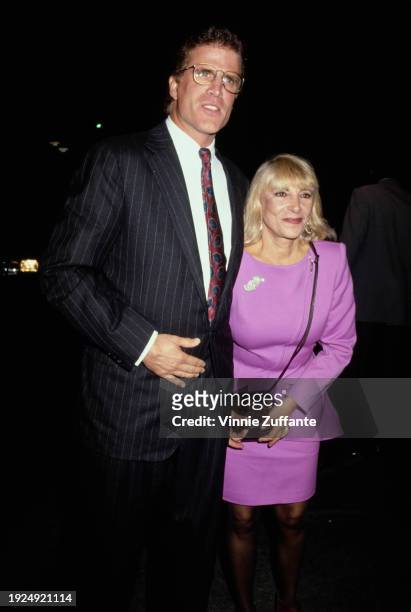 American actor Ted Danson, wearing a black pinstripe suit over a white shirt and a red-and-blue tie, and his wife, Casey Danson, who wears a lilac...