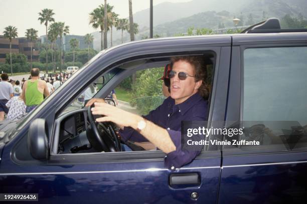 American actor Ted Danson, wearing a dark blue shirt and sunglasses as he drives a car at the 1994 Permanent Charities Committee of the Entertainment...