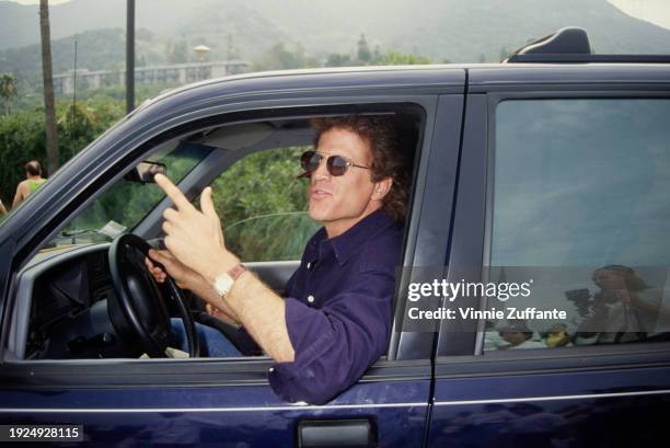 American actor Ted Danson, wearing a dark blue shirt and sunglasses as he drives a car at the 1994 Permanent Charities Committee of the Entertainment...