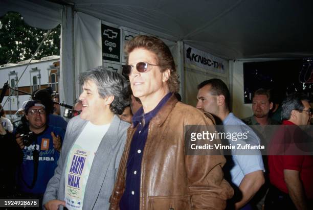 American comedian and talk show host Jay Leno, wearing a grey blazer over an 'Earth Walk' t-shirt and American actor Ted Danson, who wears a dark...