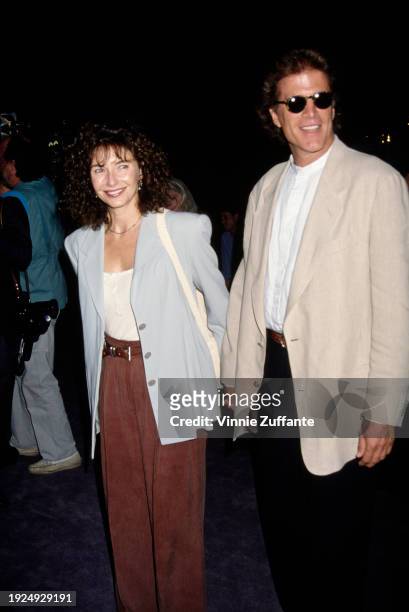 American actress Mary Steenburgen, wearing a light blue jacket and brown trousers, holding hands with American actor Ted Danson, who wears a beige...