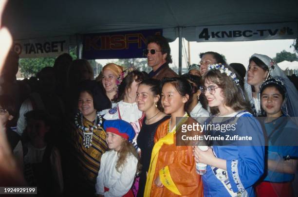 American actor Ted Danson, wearing sunglasses, poses with a group of children in national dress, at the 1994 Permanent Charities Committee of the...