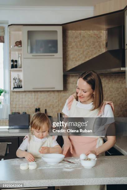 little girl and her mother cooking in the kitchen. - lady cooking confused imagens e fotografias de stock