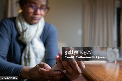 black professional woman using smart phone at desk