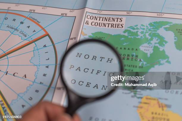 north pacific ocean, magnifying glass close up with colorful world map. - karachi map stock pictures, royalty-free photos & images