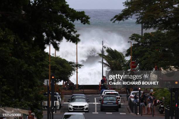 People watches waves crashing in Saint-Denis de la Reunion on January 14, 2024 as authorities on France's Indian Ocean Reunion Island urged residents...