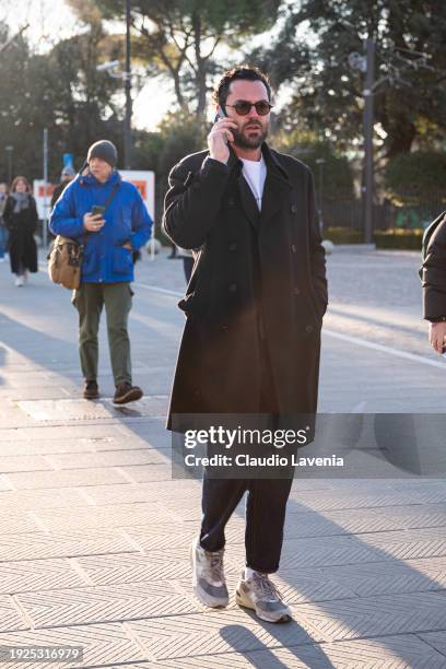 Guest, wearing a white t-shirt, denim pants and black long coat, is seen during Pitti Immagine Uomo 105 at Fortezza Da Basso on January 11, 2024 in...