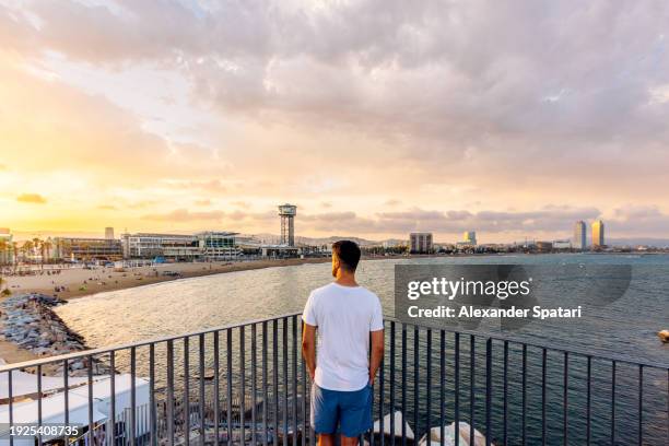 rear view of a man looking at barceloneta beach at sunset, barcelona, spain - barceloneta beach stock pictures, royalty-free photos & images