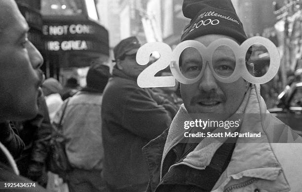 View of a reveler wearing a pair of 2000 glasses in preparation for the Millennium on New Year's Eve 2000 in Times Square, New York, New York,...