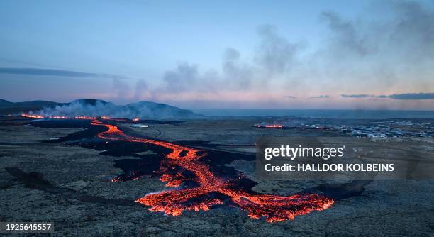 Lava explosions and billowing smoke are seen near residential buildings in the southwestern Icelandic town of Grindavik after a volcanic eruption on...