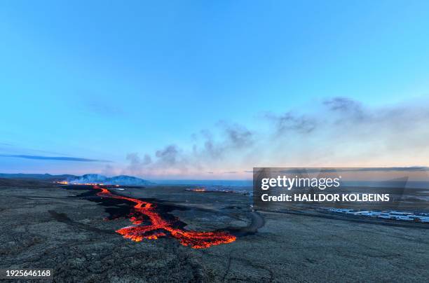 Lava explosions and billowing smoke are seen near residential buildings in the southwestern Icelandic town of Grindavik after a volcanic eruption on...