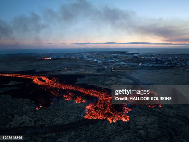 Lava explosions and billowing smoke are seen near residential buildings in the southwestern Icelandic town of Grindavik after a volcanic eruption on...