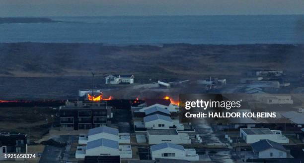 Lava explosions and billowing smoke are seen near residential buildings in the southwestern Icelandic town of Grindavik after a volcanic eruption on...