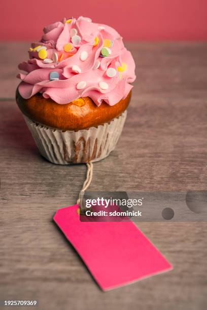 single cupcake with pink icing with blank tag - fundraising stock pictures, royalty-free photos & images