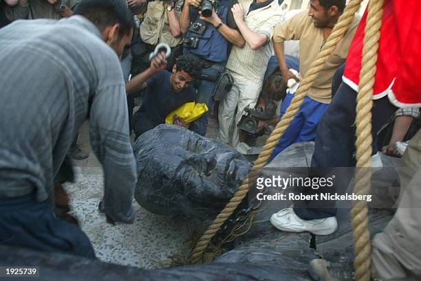 Iraqi civilians destroy a Saddam Hussein statue after toppling it with help from US Marines from the Marine 1st Division near the Palestine Hotel...