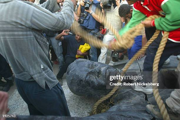 Iraqi civilians destroy a Saddam Hussein statue after toppling it with help from US Marines from the Marine 1st Division near the Palestine Hotel...