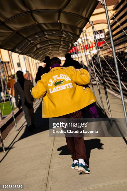 Guest, wearing brown pant, purple scarf and yellow Lacoste jacket, is seen during Pitti Immagine Uomo 105 at Fortezza Da Basso on January 11, 2024 in...