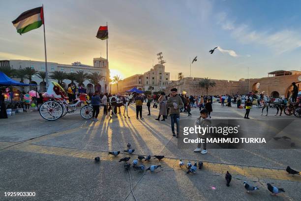 Palestinian flag flutters next to a Libyan flag as people gather in Martyrs square in the capital Tripoli on January 14, 2024.