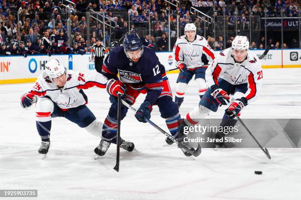 Nick Bonino of the New York Rangers skates with the puck against Ethan Bear and Aliaksei Protas of the Washington Capitals at Madison Square Garden...