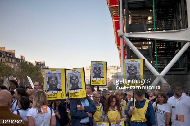 People hold Amnesty International placard as he takes part in a demonstration in Paris, on September 16, 2011 as part of worldwilde protest rallies,...