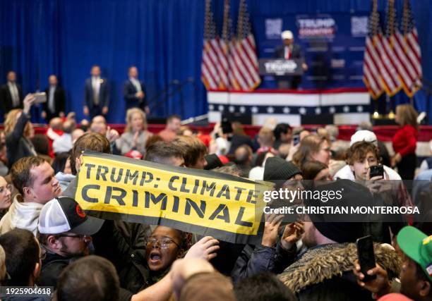 Climate protesters interrupt former US president and Republican presidential hopeful Donald Trump as he speaks at a "commit to caucus rally" in...