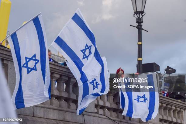 Protesters hold Israeli flags during the demonstration. Thousands of pro-Israel protesters gathered in Trafalgar Square to mark 100 days since the...