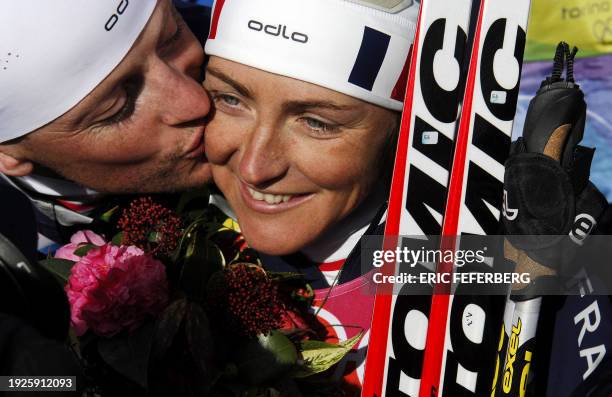 Florence Baverel-Robert of France smiles as her husband Julien kisses her after she won the gold in the 7.5km sprint of the women's biathlon at the...