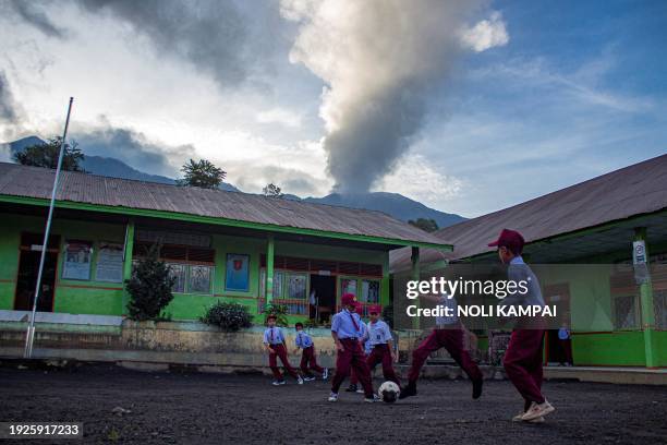 Pupils play soccer at a school as Mount Marapi spews hot smoke in Agam, West Sumatra on January 15, 2024.