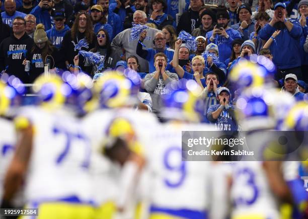 Detroit Lions fans cheer as the Los Angeles Rams offense huddles during the first quarter of an NFL wild-card playoff football game at Ford Field on...