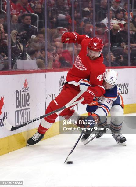 Warren Foegele of the Edmonton Oilers battles for the puck against Jeff Petry of the Detroit Red Wings during the first period at Little Caesars...