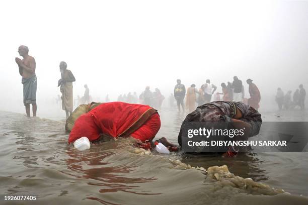 Pilgrims take a holy dip amid dense fog at the confluence of River Ganges and the Bay of Bengal during 'Gangasagar Mela' on the occasion of the Hindu...