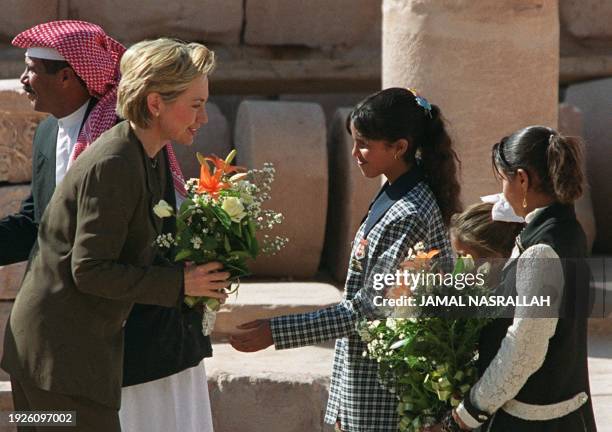 First Lady Hillary Clinton receives flowers 12 November 1999 from Bedouin girls at the entrance of a church during her visit to the southern city of...