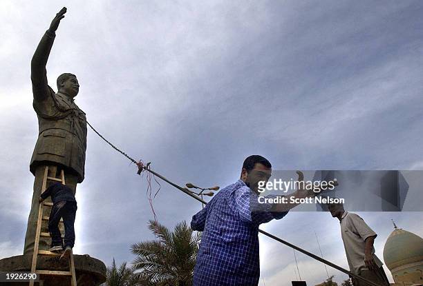 An Iraqi man directs a crowd helping pull down a statue of ousted Iraqi President Saddam Hussein during an impromptu celebration on the streets April...