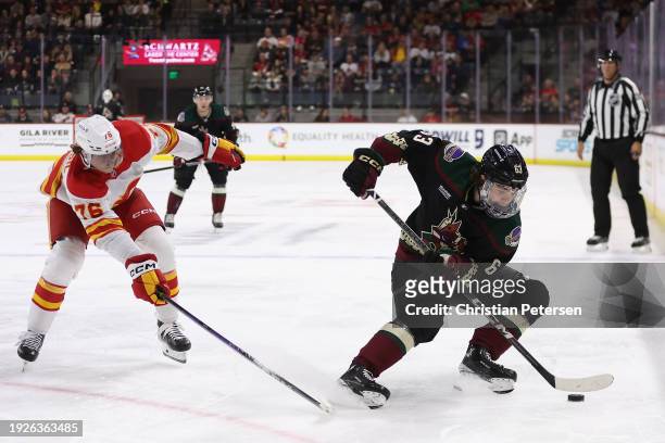 Matias Maccelli of the Arizona Coyotes skates with the puck against Martin Pospisil of the Calgary Flames during the second period of the NHL game at...