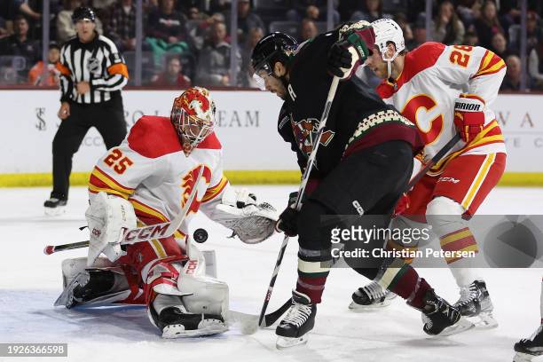 Goaltender Jacob Markstrom of the Calgary Flames makes a save on the puck as Nick Schmaltz of the Arizona Coyotes skates in during the second period...